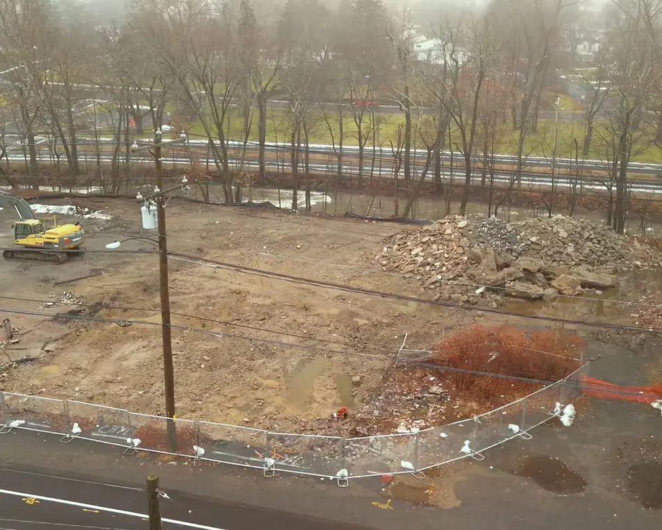 Development and earthwork at a riverside power-ready industrial site with excavator and cleared land