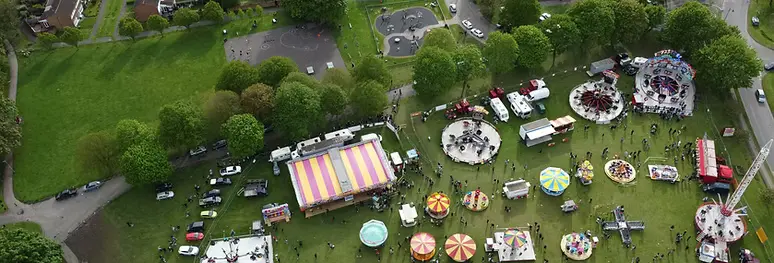 Aerial view of a community gathering in a green park with festival tents and open space near resilient infrastructure
